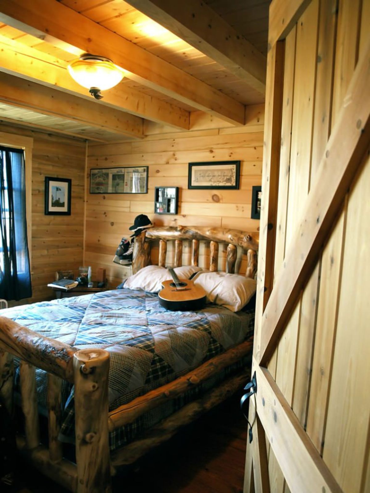 barn door open into bedroom with log bed frame and blue bedding on bed