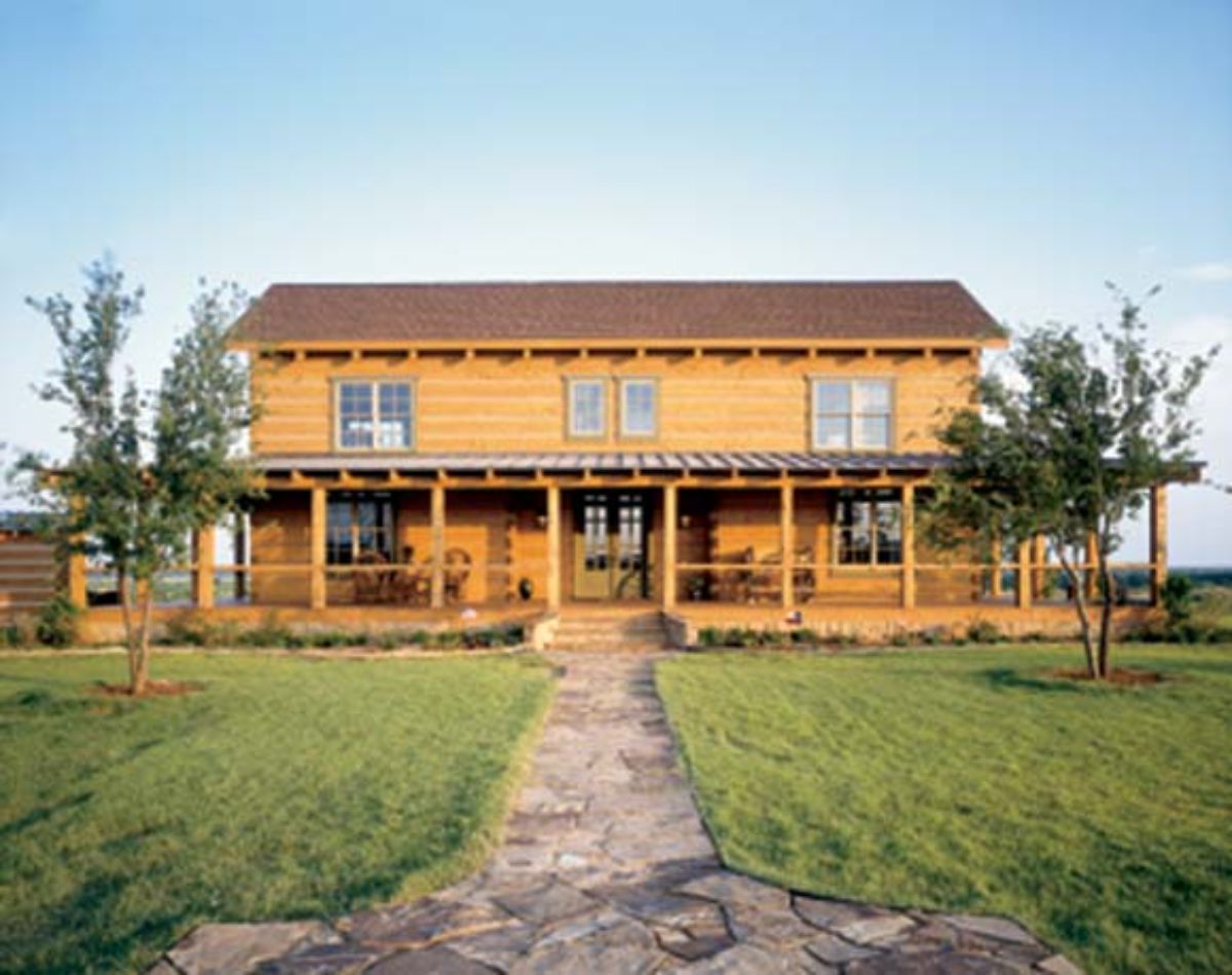 front of log cabin with light wood siding and two stories with covered porch on front