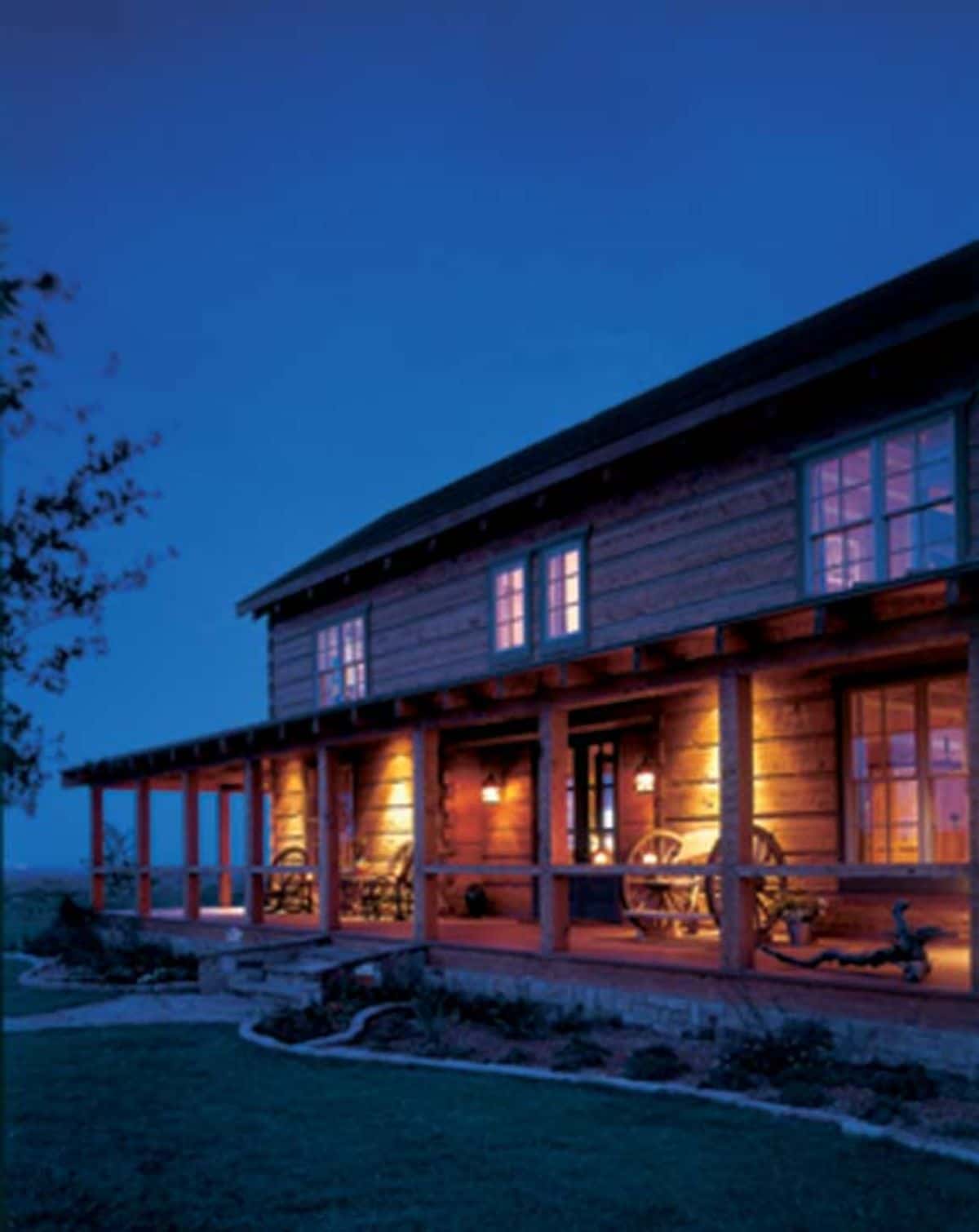 covered porch on front of cabin with porch lights after sunset