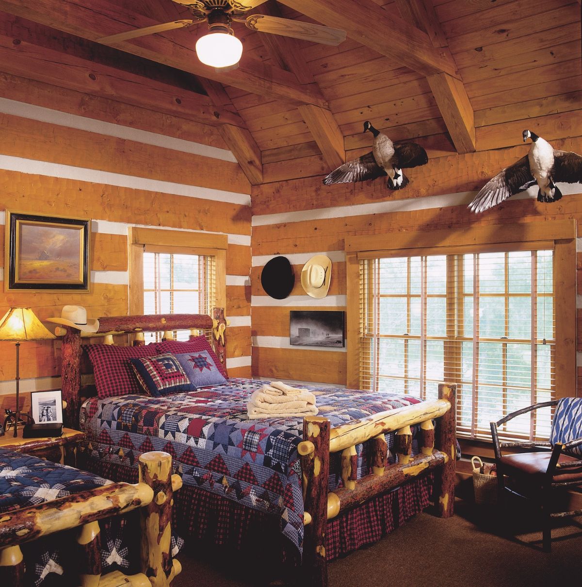dark wood log bed with blue bedding in cabin with french doors on side of room