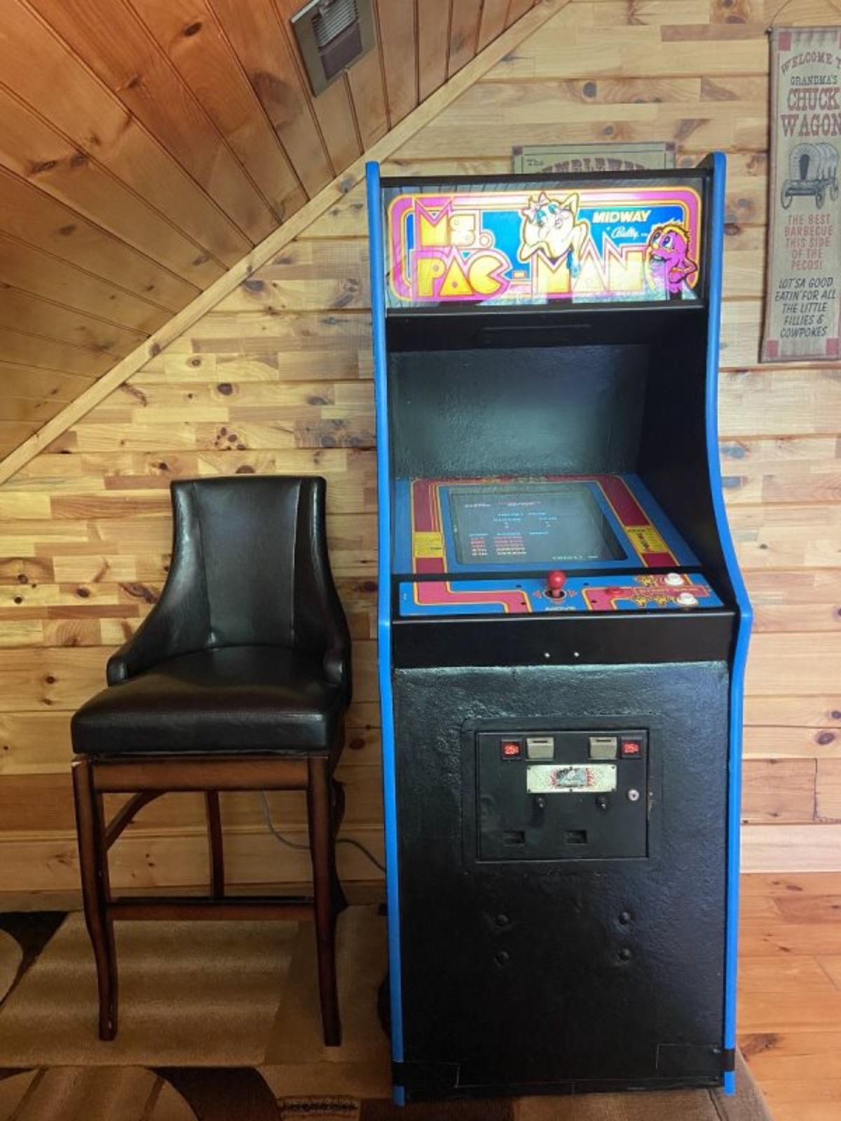 arcade game with black chair against wall of loft