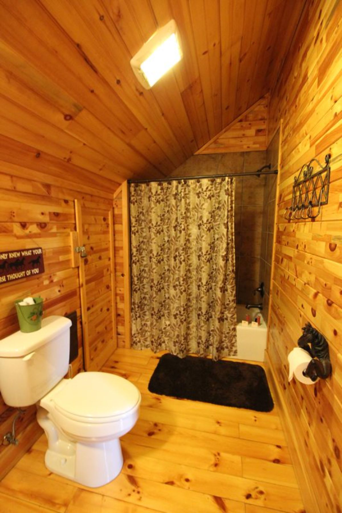 white toilet in log cabin bathroom with shower in background