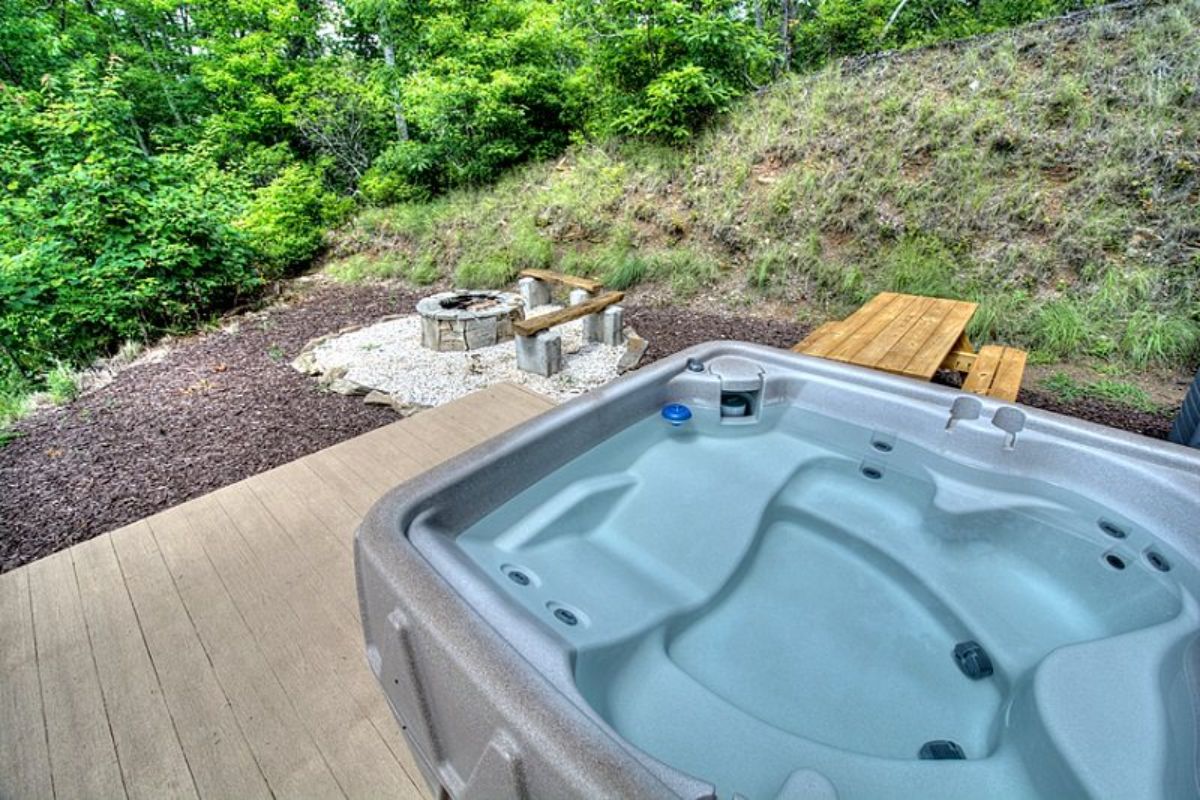 hot tub on base of log cabin deck with firepit below