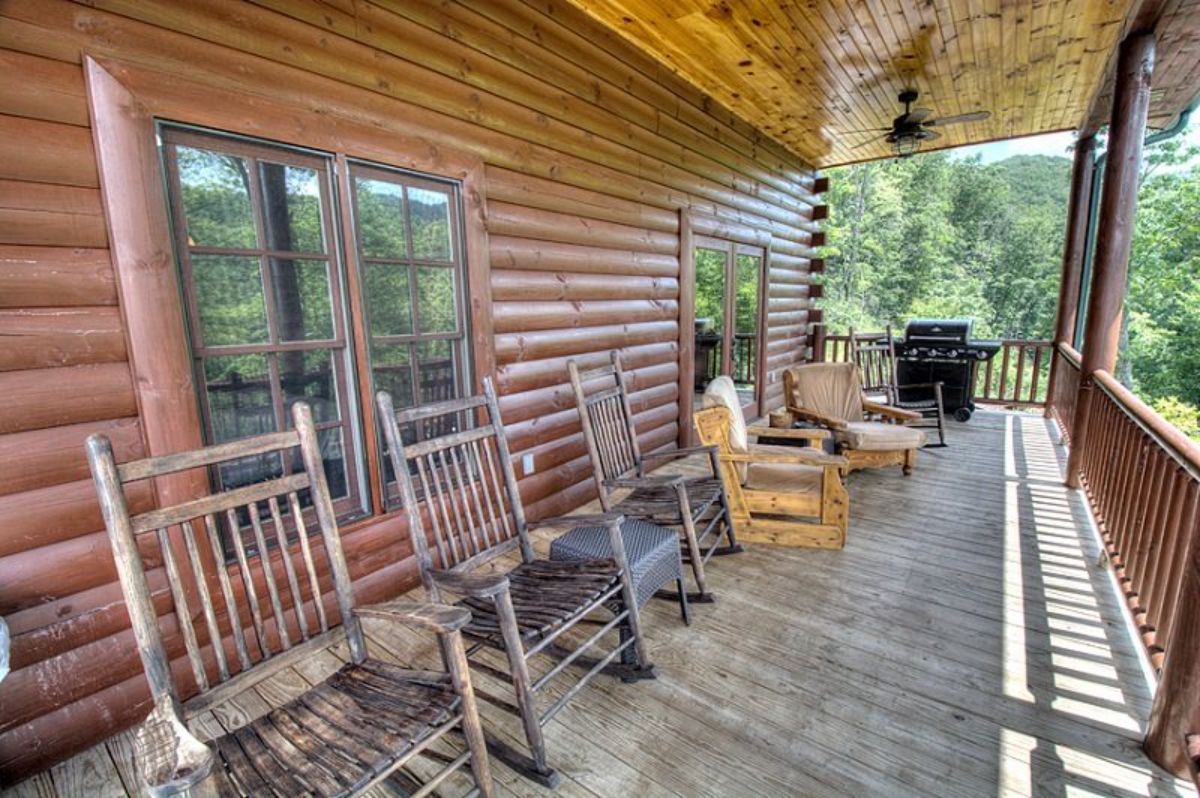 rocking chairs lined up against log cabin wall with covered deck