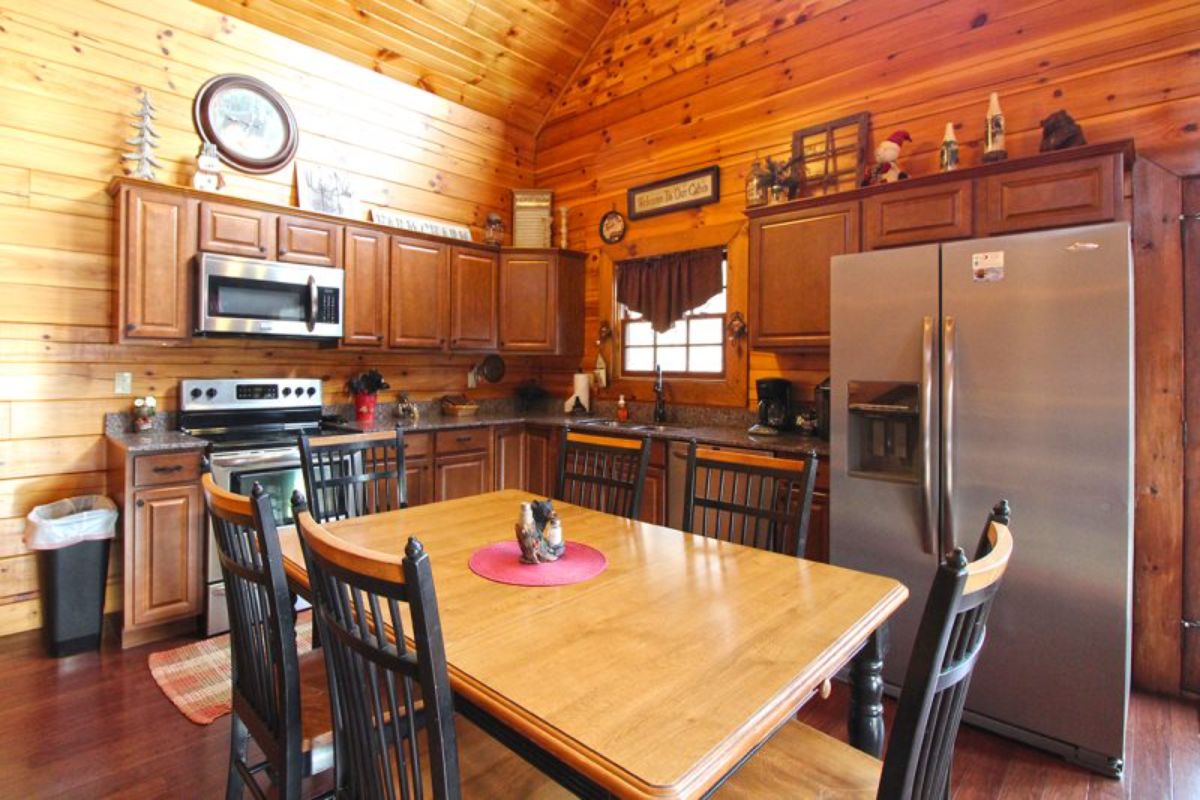 light wood table top with black chairs and stainless steel refrigerator in background