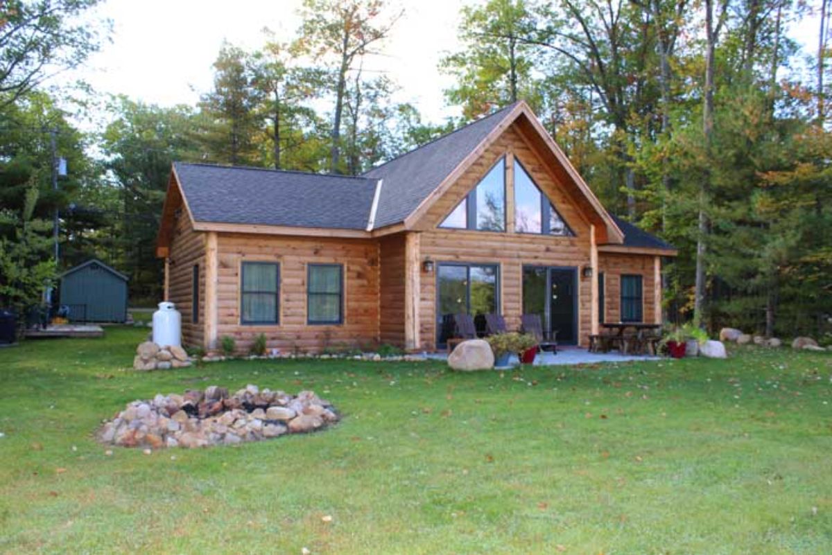 back of log cabin with patio by wall of windows