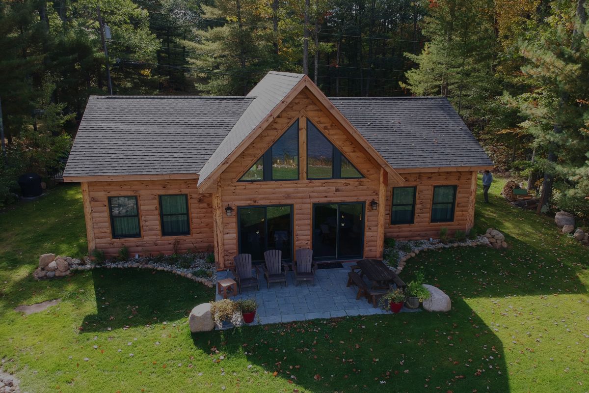 view of log cabin from above with drone looking at concrete patio