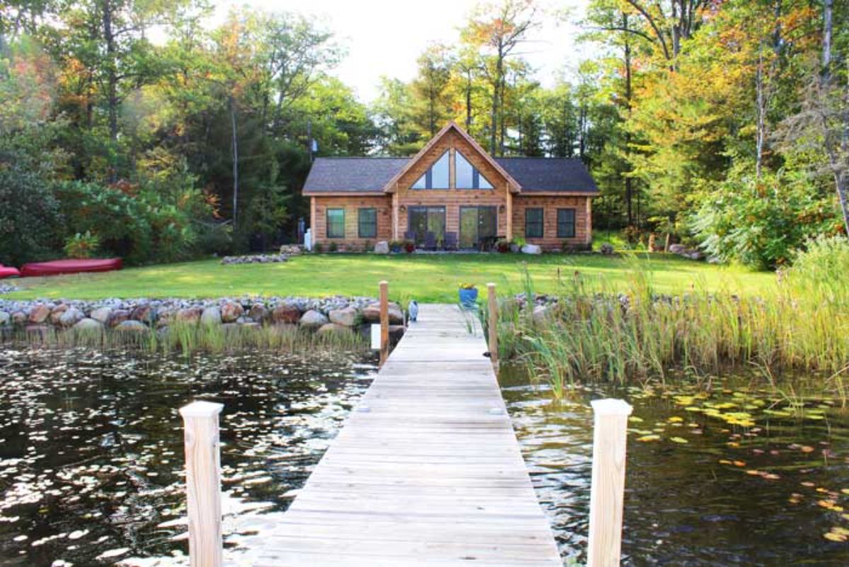 view across wooden dock to log cabin against woodline