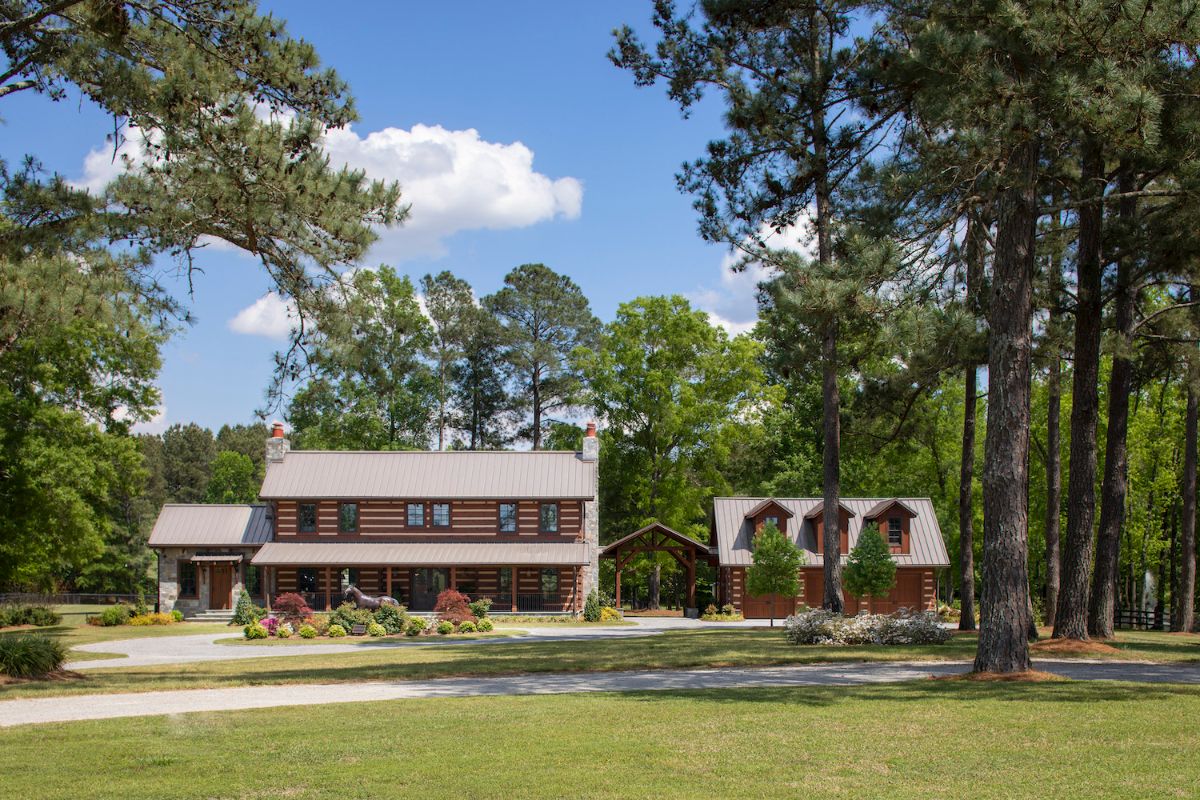 log cabin with detached garage next to it behind treeline