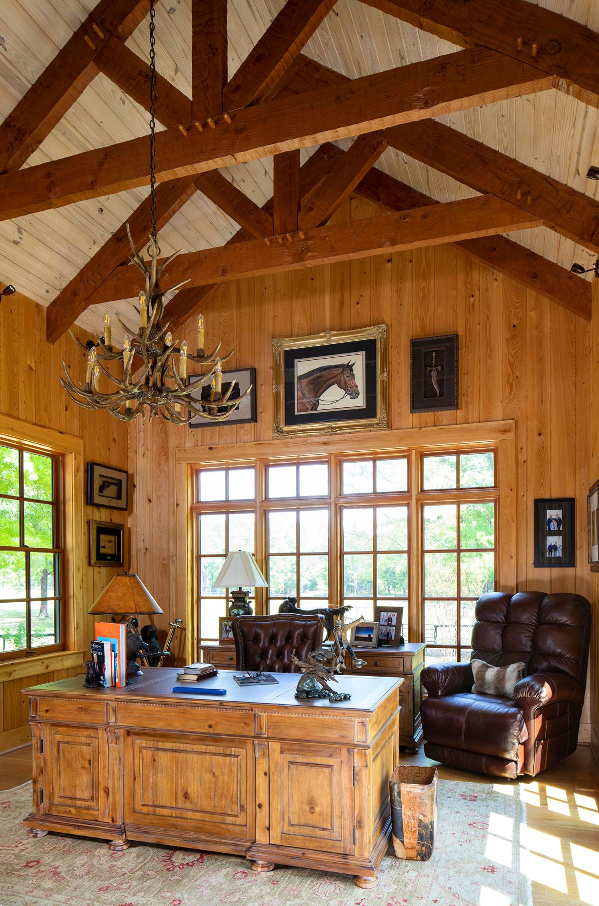 desk in foreground with wall of windows in background and leather chair on right