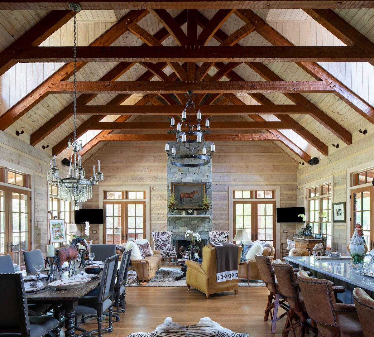 view across living room inside log cabin with exposed dark wood beams above and fireplace on back wall