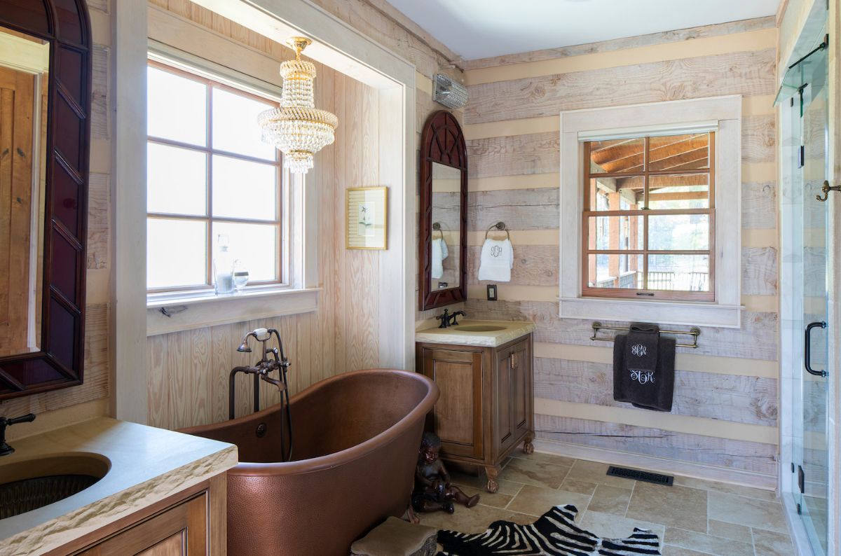copper soaking tub beneath window with light wood and chinking on walls