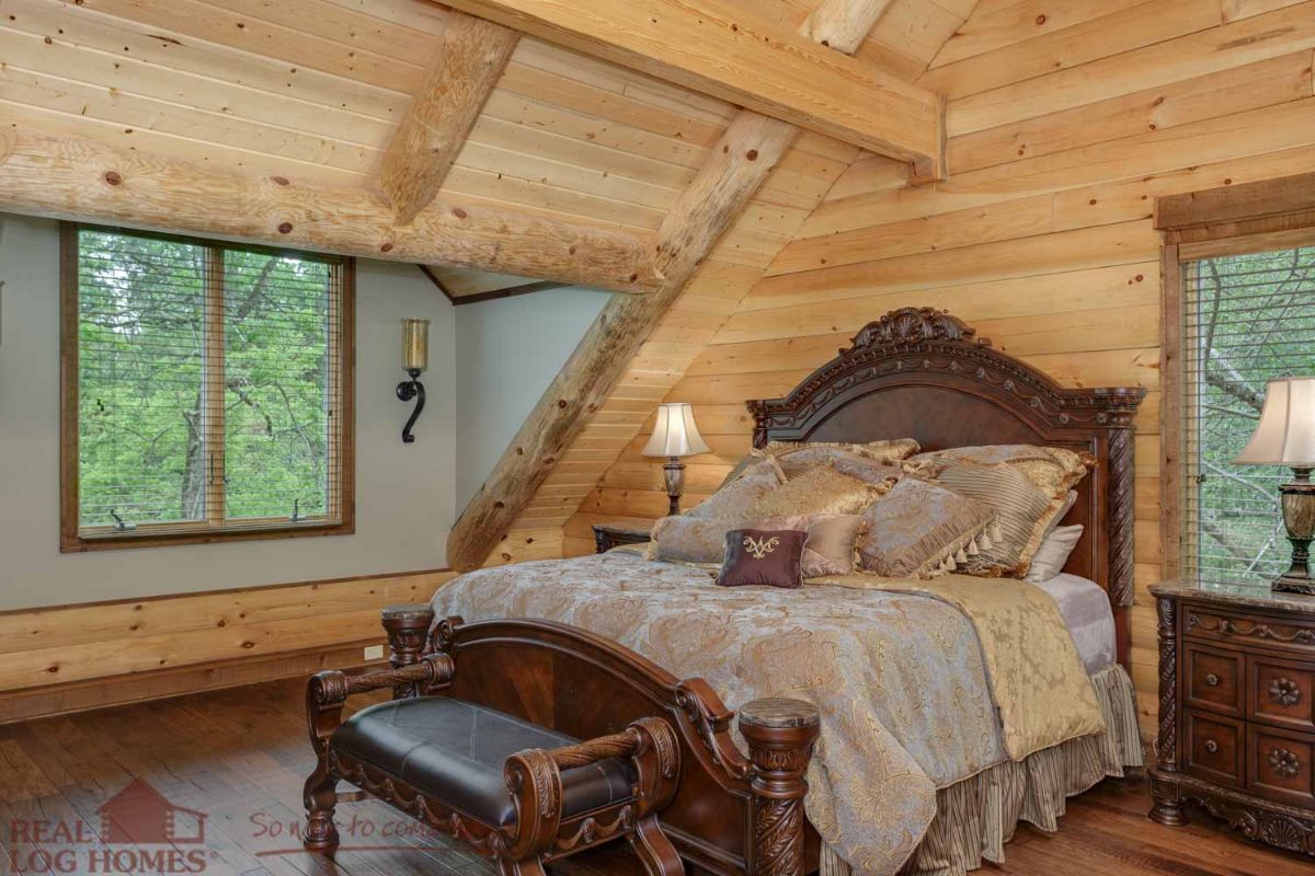 dark wood bedframe with light bedding beneath dormer window in cabin
