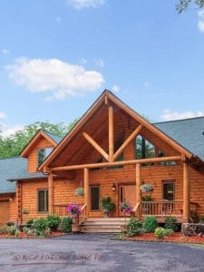 medium wood stain on log cabin with covered porch and green roof