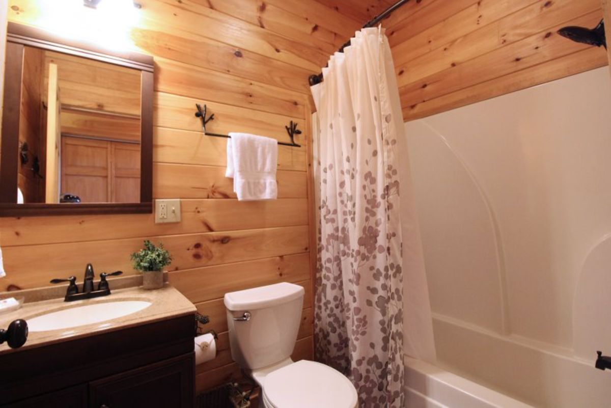 floral shower curtain hanging on white shower in bathroom