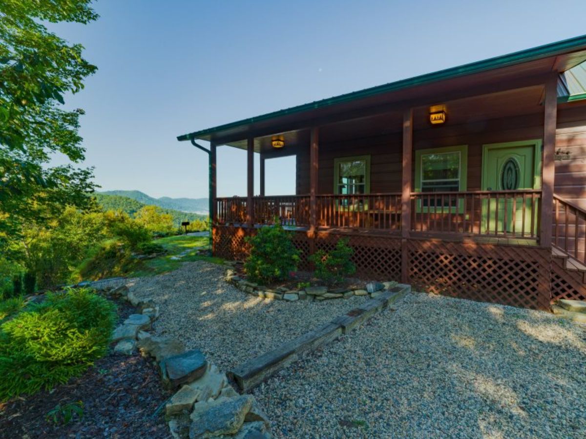 side of log cabin showing porch and gravel walkway