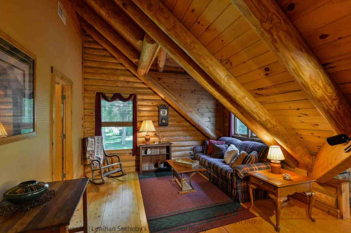 sofa and chairs in loft landing of log cabin with eindow on end