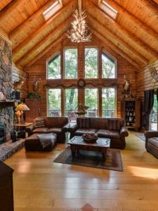 log cabin great room with wall of windows and brown leather sofas