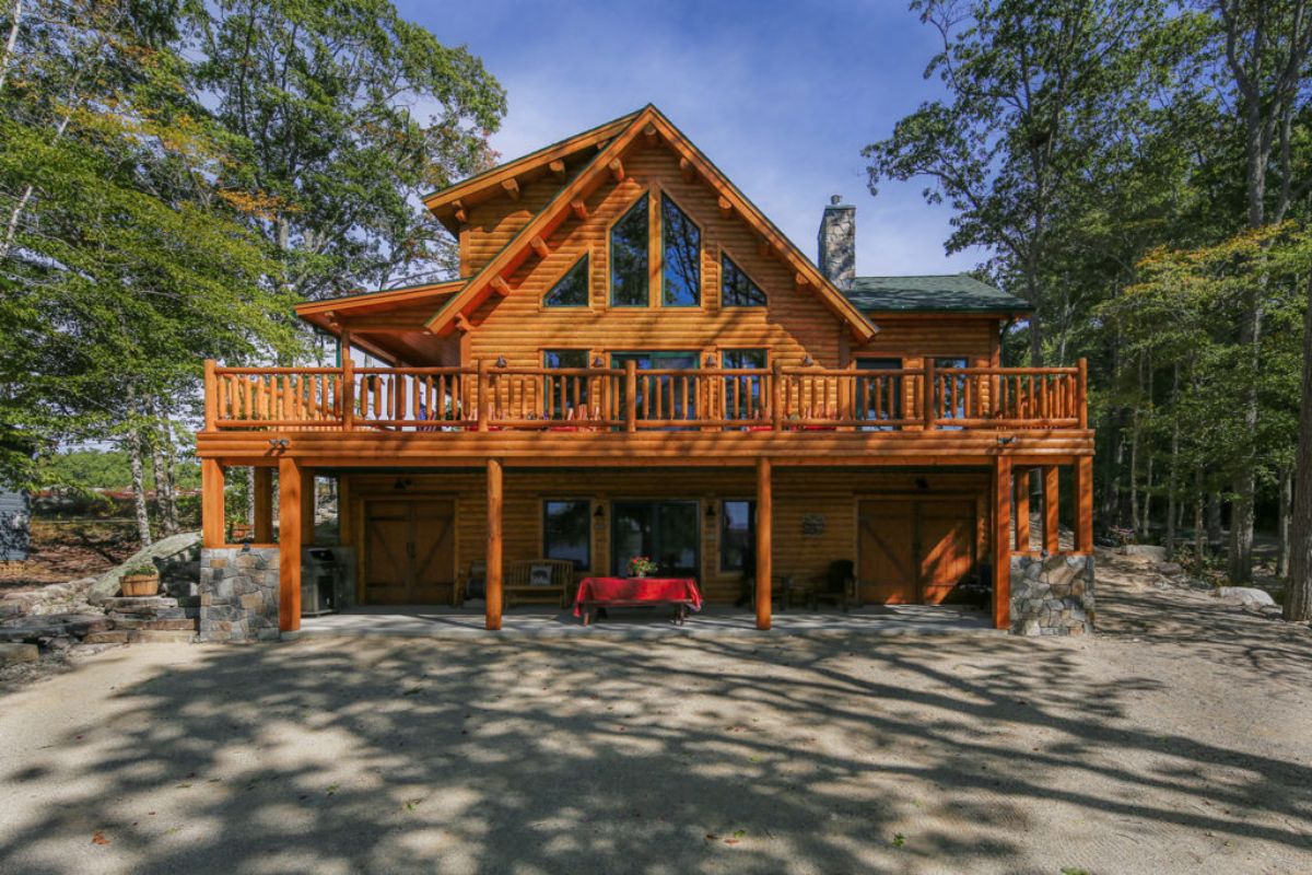 log cabin with three floors and wall of windows facing outside to lawn