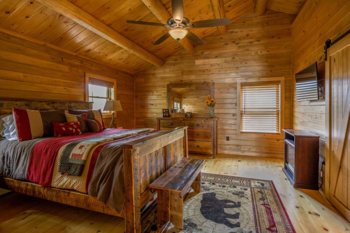 quilt on bed beneath ceiling fan in log cabin bedroom