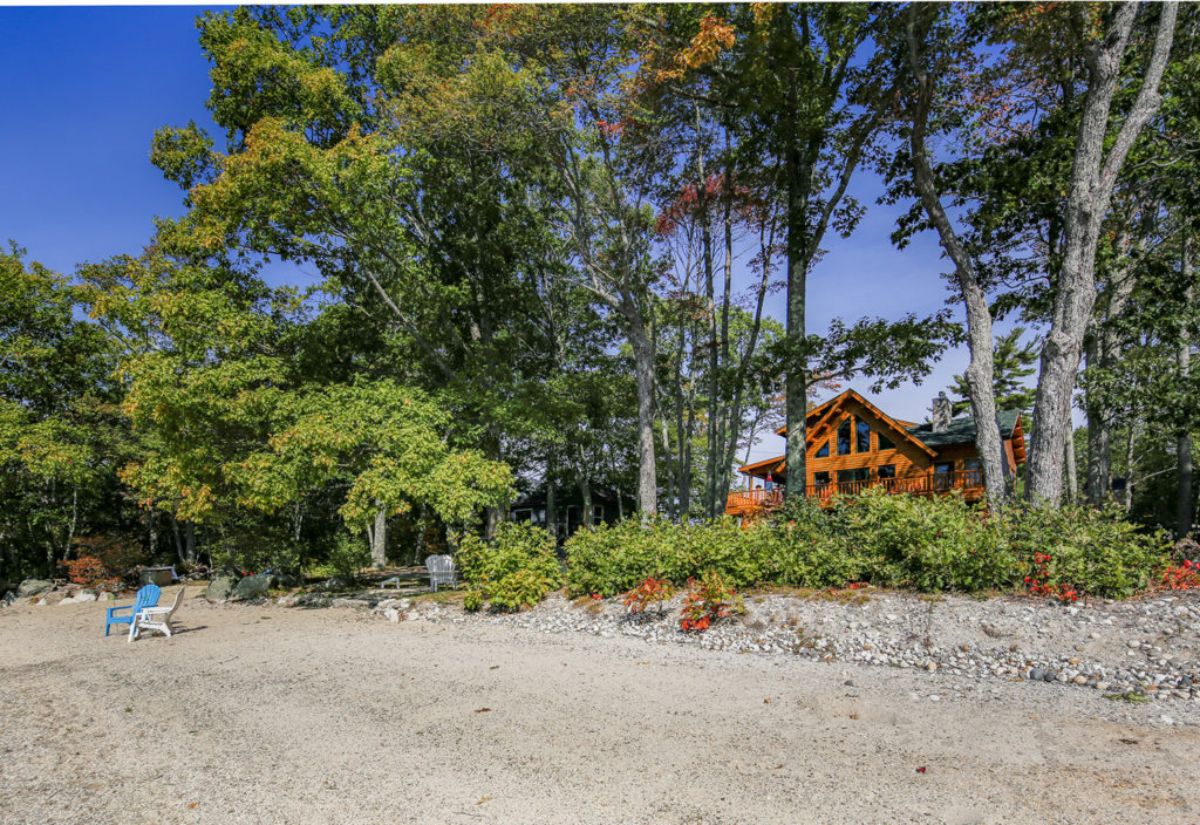 gravel driveway to log cabin behind trees