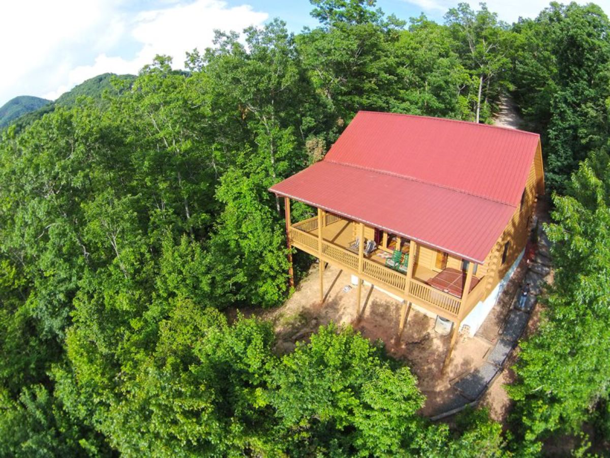 red roof cabin on hill surrounded by trees