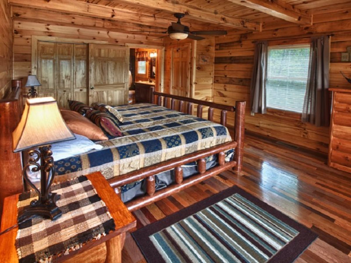 striped rug on floor beside bed in log cabin