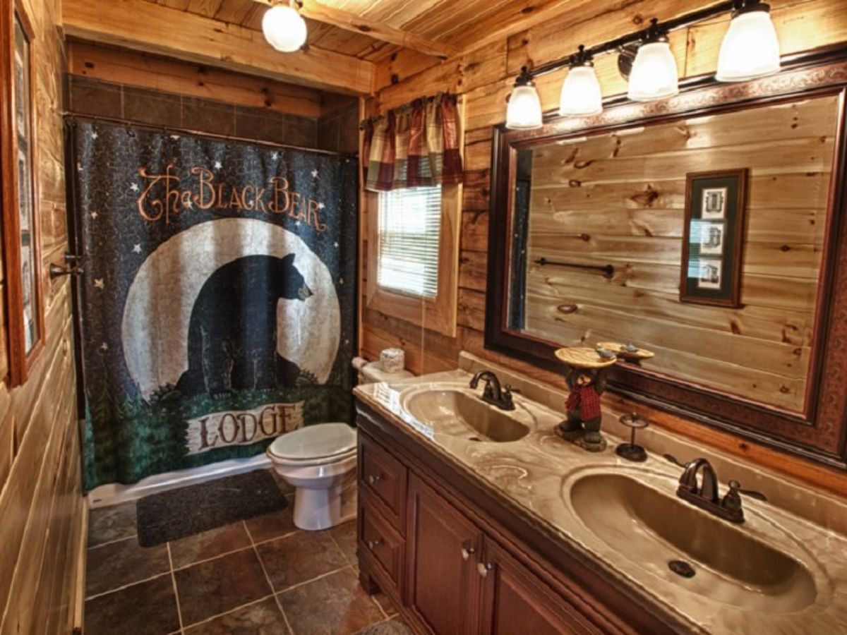 bear on shower curtain in log cabin bathroom with two sinks