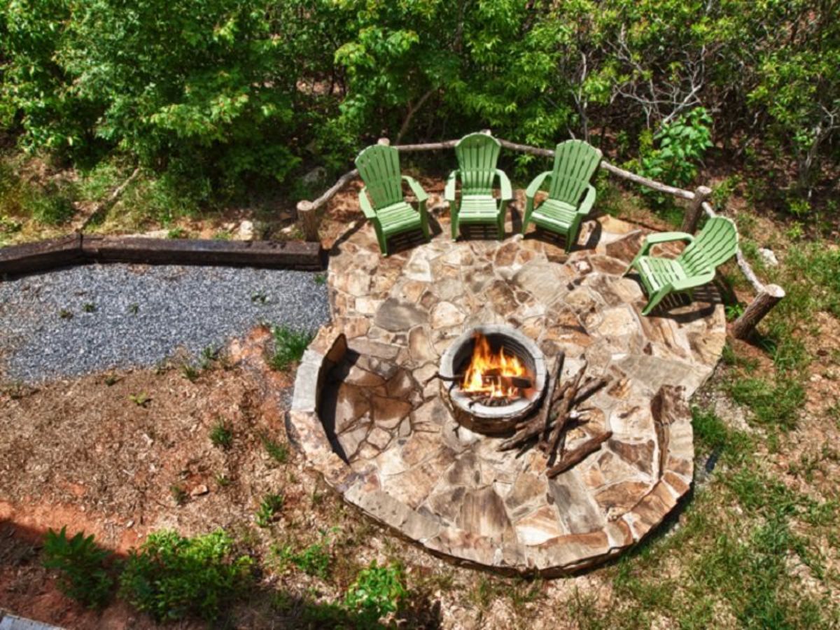 firepit in center of rock deck with green chairs
