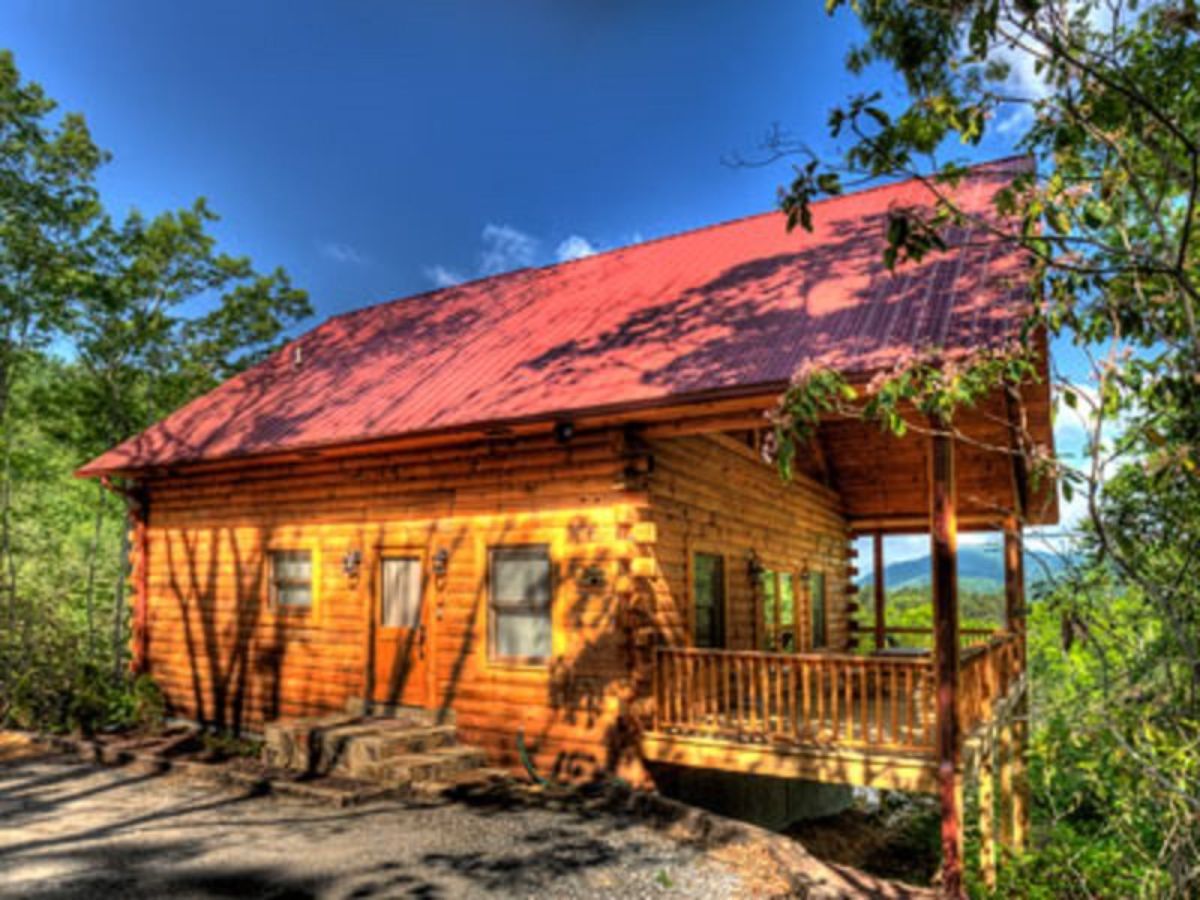 red roof on log cabin with light wood walls and porch on side