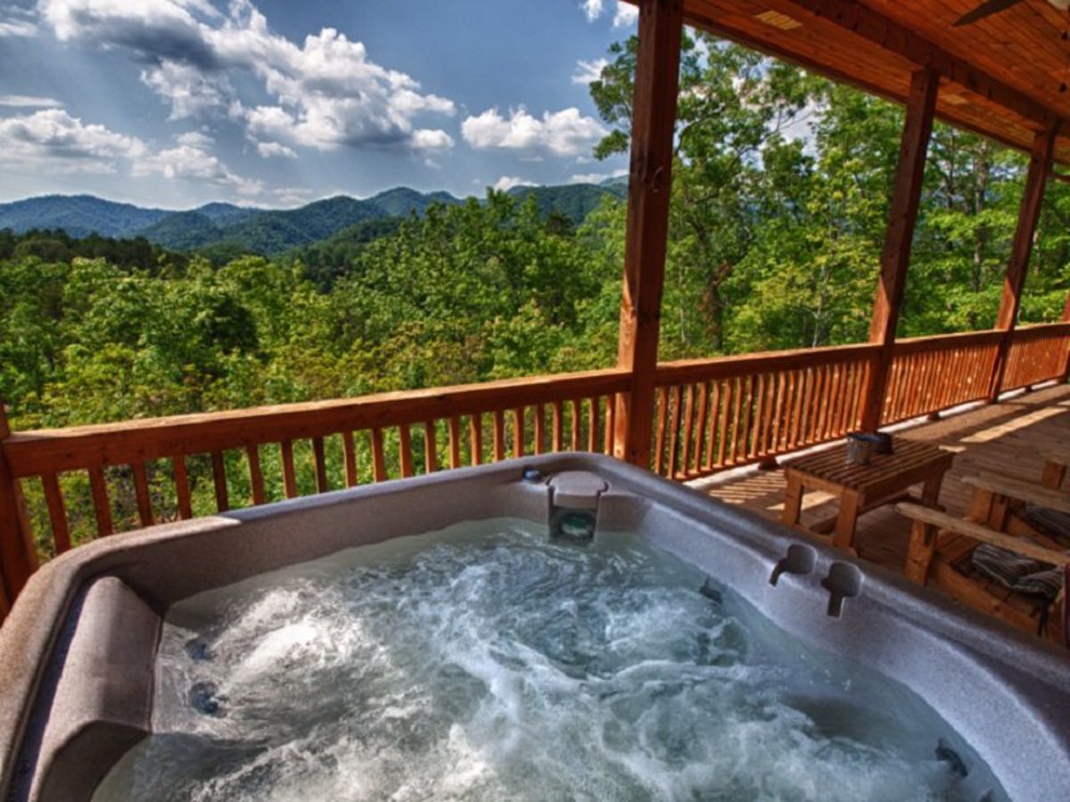 hot tub on deck looking out over green trees on mountains