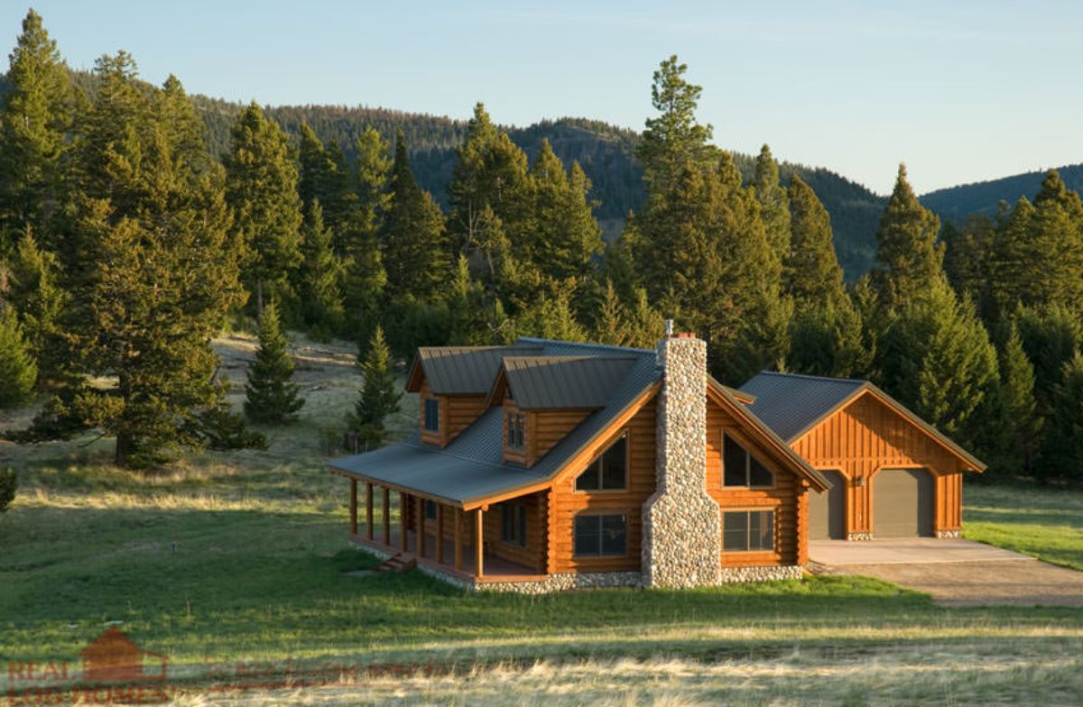 two story log cabin in field with trees in background and chimney on side of home