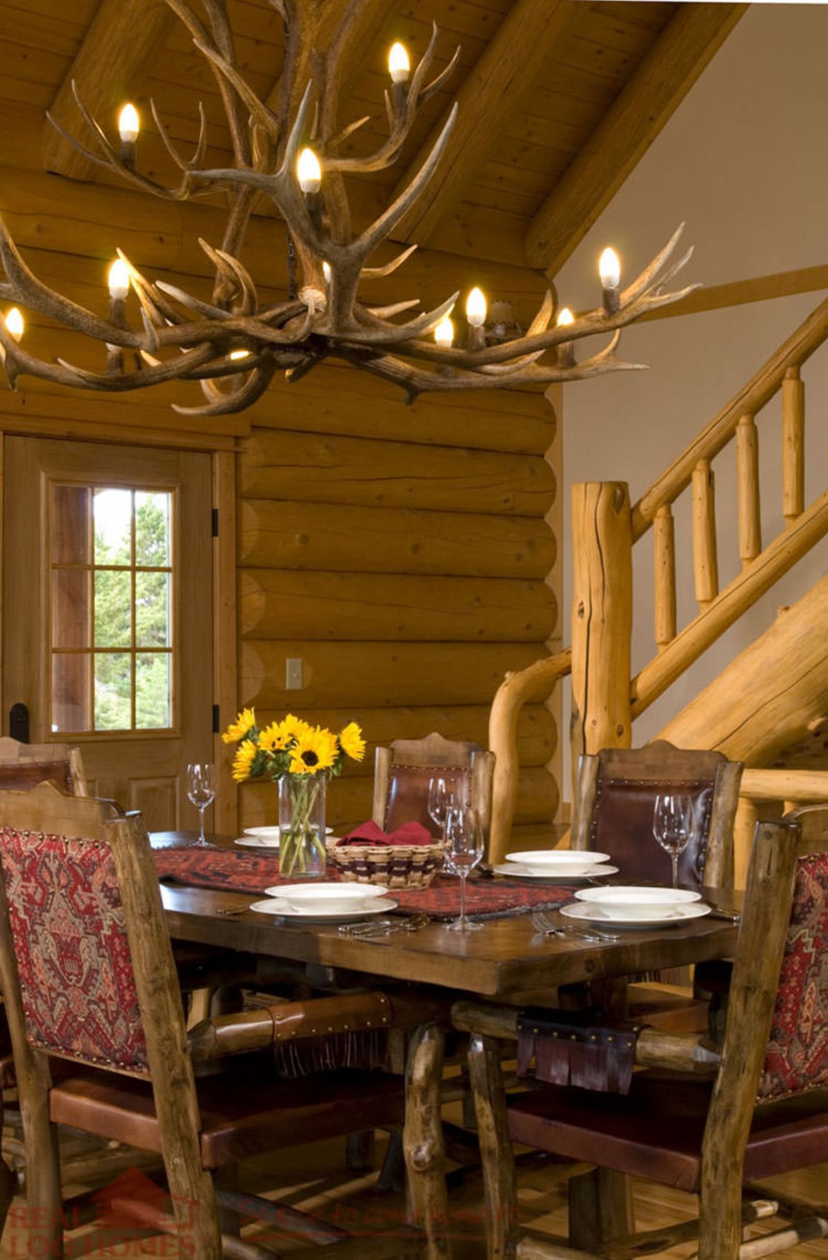 formal dining table with upholstered chairs beneath antler chandelier