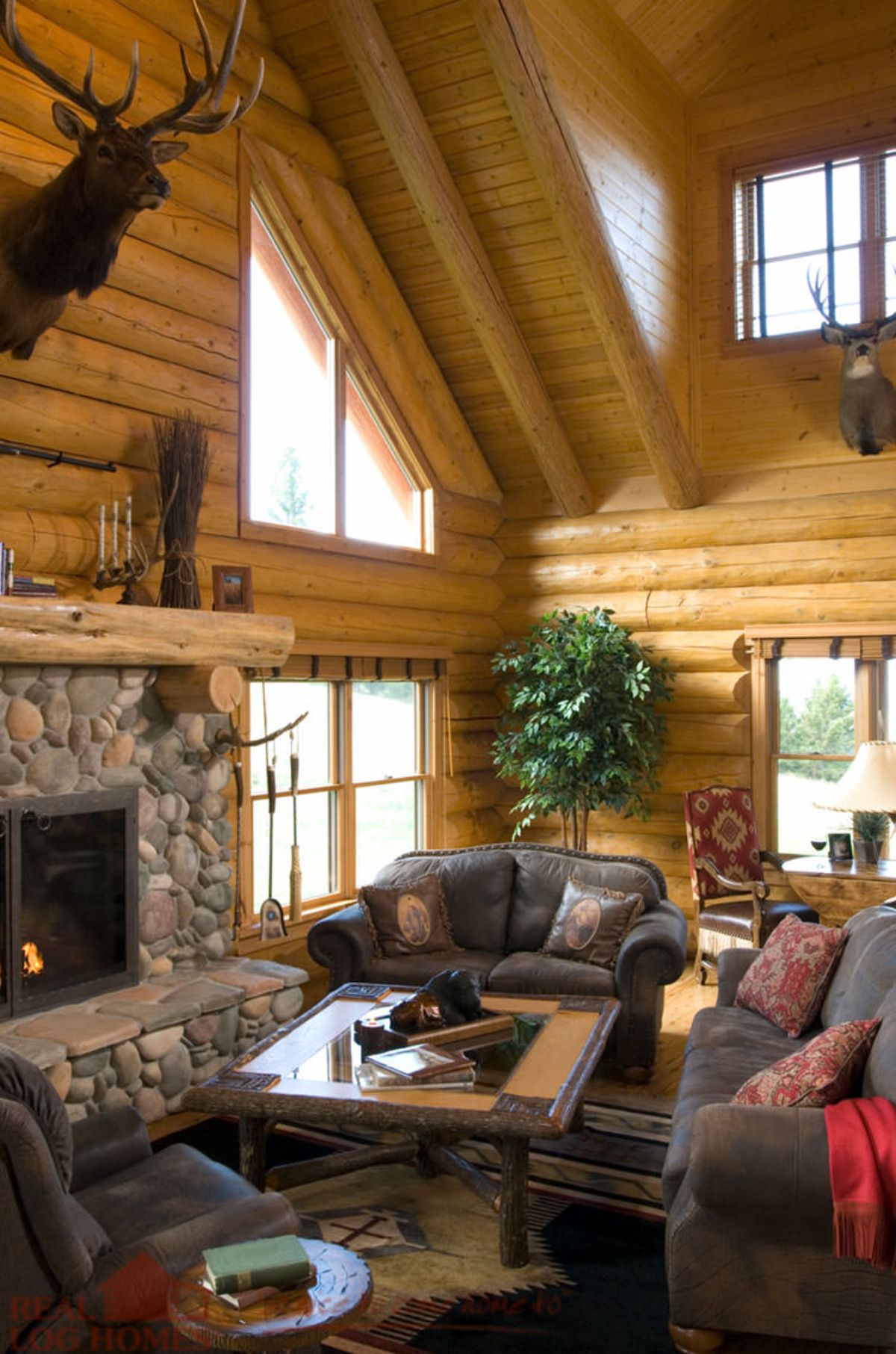 stone fireplace on left of log cabin room with leather sofas