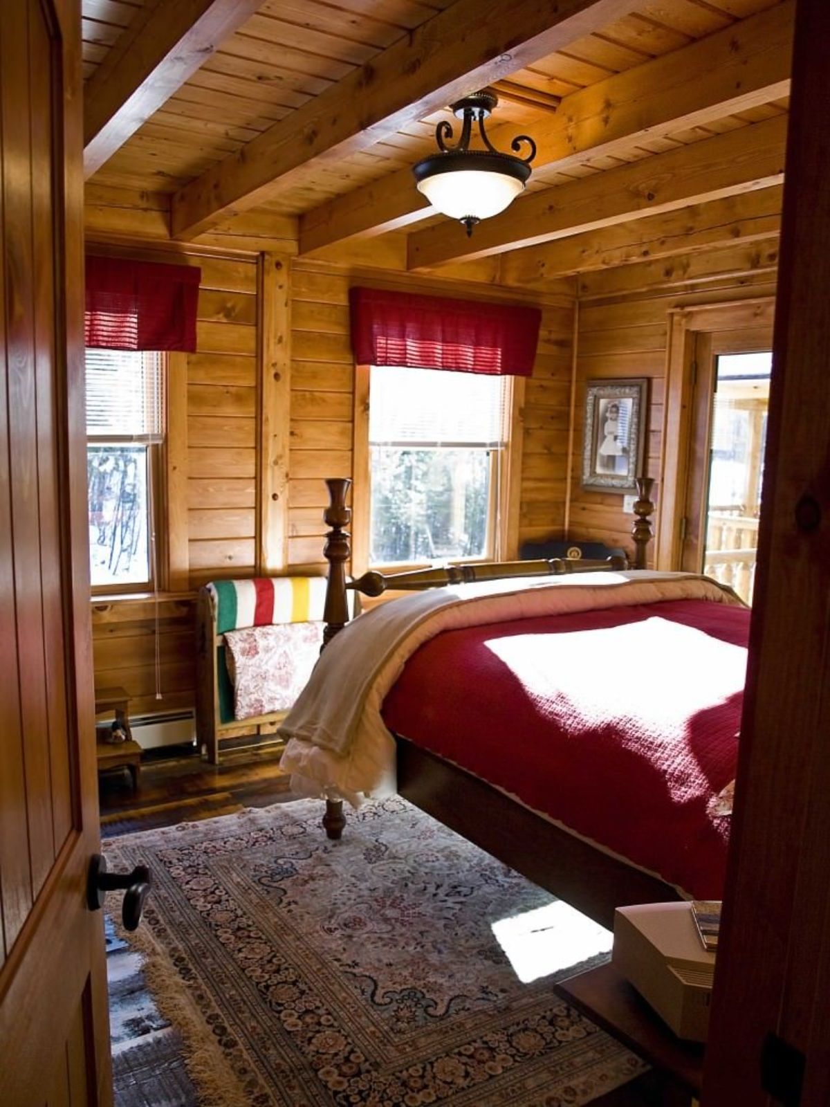 view into bedroom with wood bedframe and red curtains