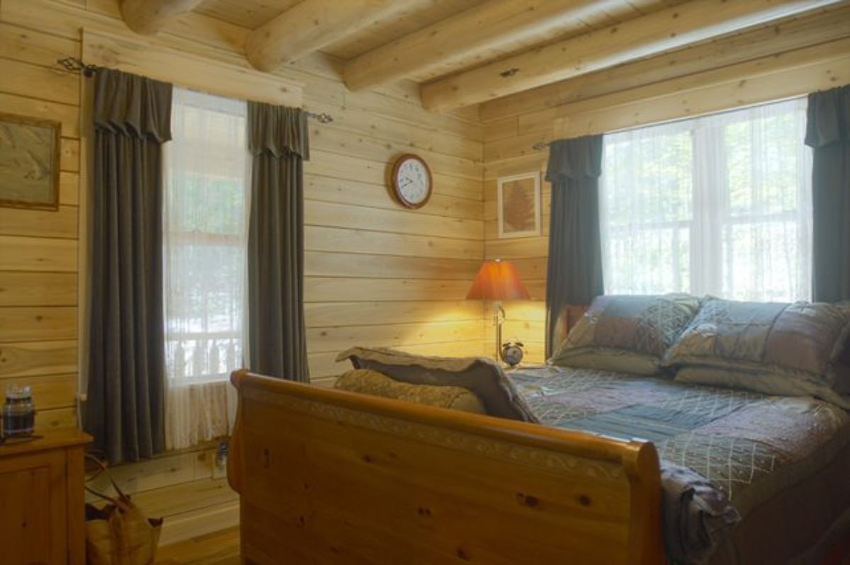 light wood sleigh bed in room with dark curtains on windows