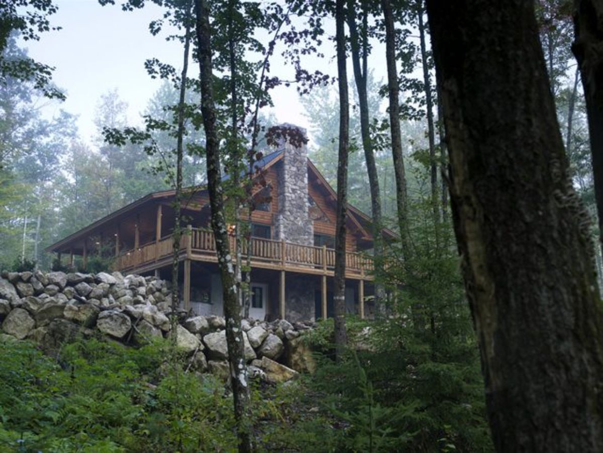 side of log cabin with chimney view through wooded area