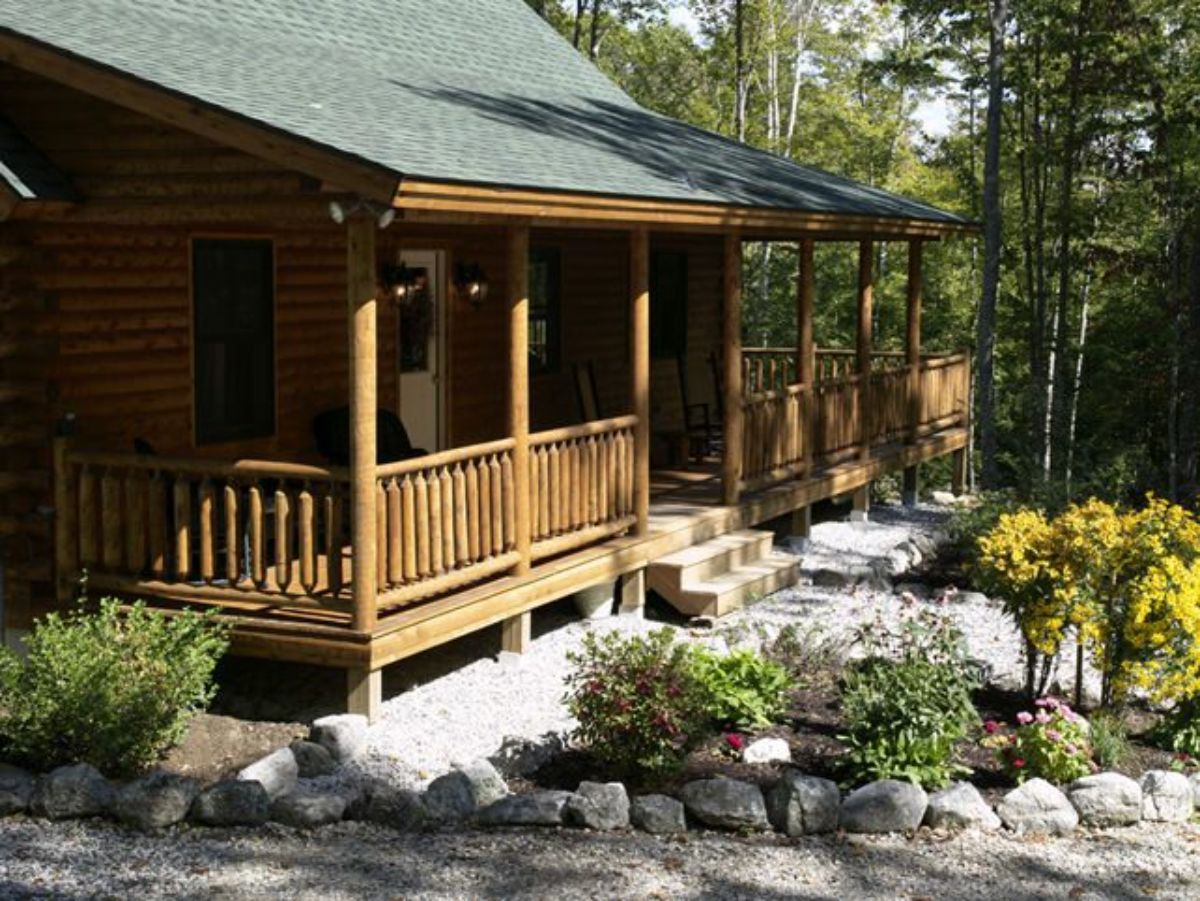 light wood porch on front of log cabin with green roof
