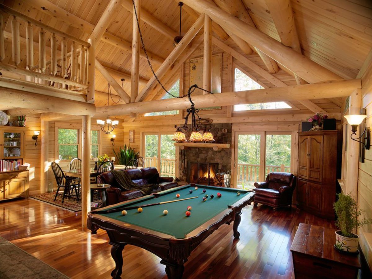 green topped pool table below light wood beams in log cabin living room