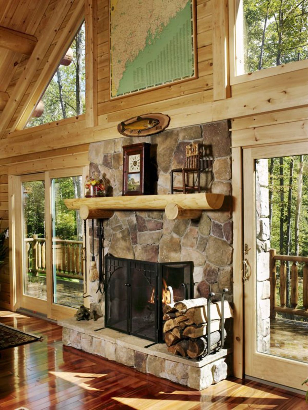 stone fireplace with light wood mantle against wall of windows