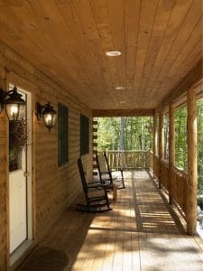 covered porch with rocking chairs against wall of log cabin