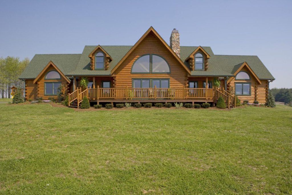 back of log cabin with green roof in field