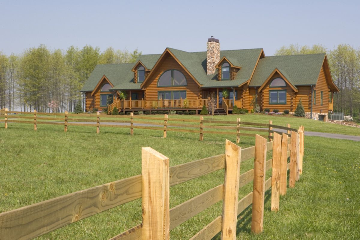 back of log cabin with green roof in field