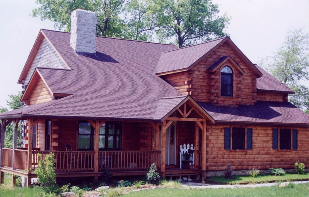 dark wood log cabin with dormer window above front entrance