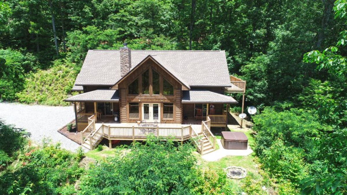 great room of log cabin with open deck and arched roof facing outward