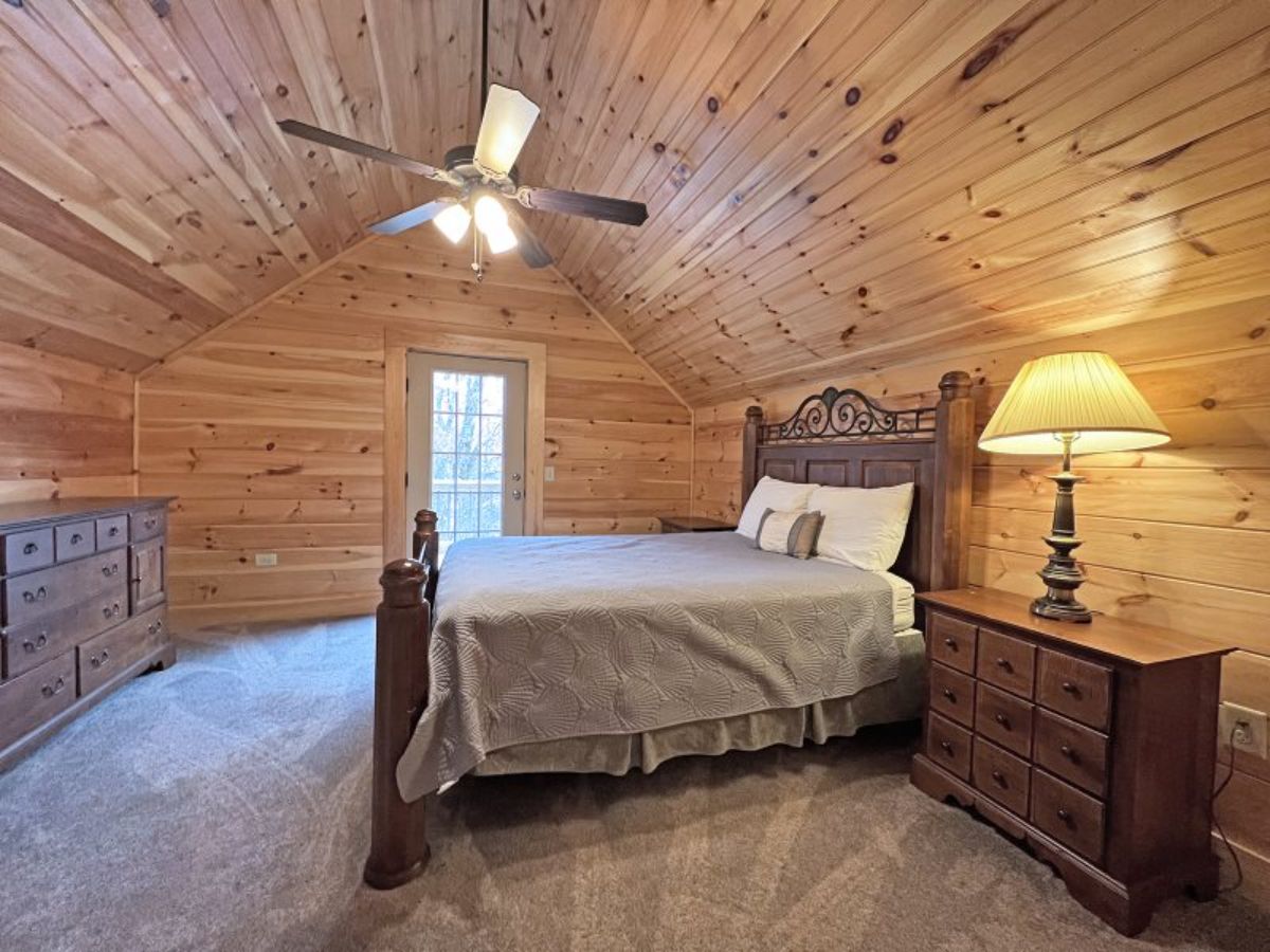 loft bedroom with sleigh bed beneath ceiling fan and arched ceiling