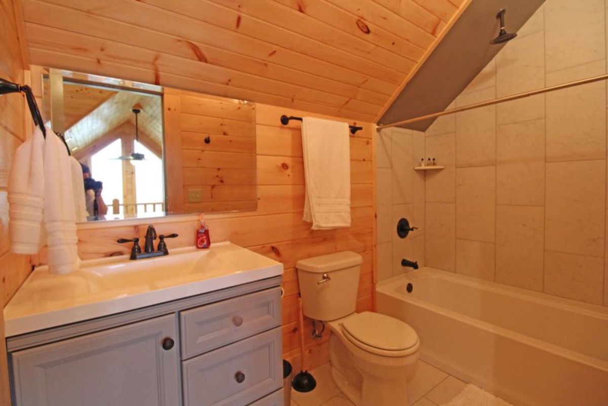 loft bathroom with white shower and bathtub combination on right wall