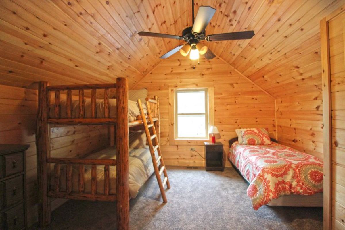 bunkbeds on left and single bed on right with ceiling fan in center of room