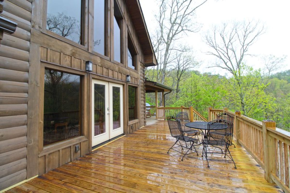 open deck on log cabin with bistro set by railing