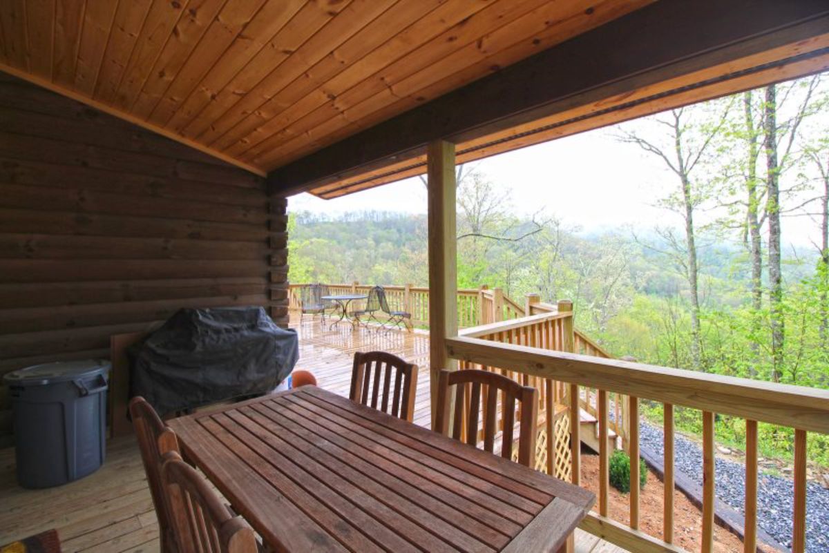 wood table under covered porch on back deck of log cabin